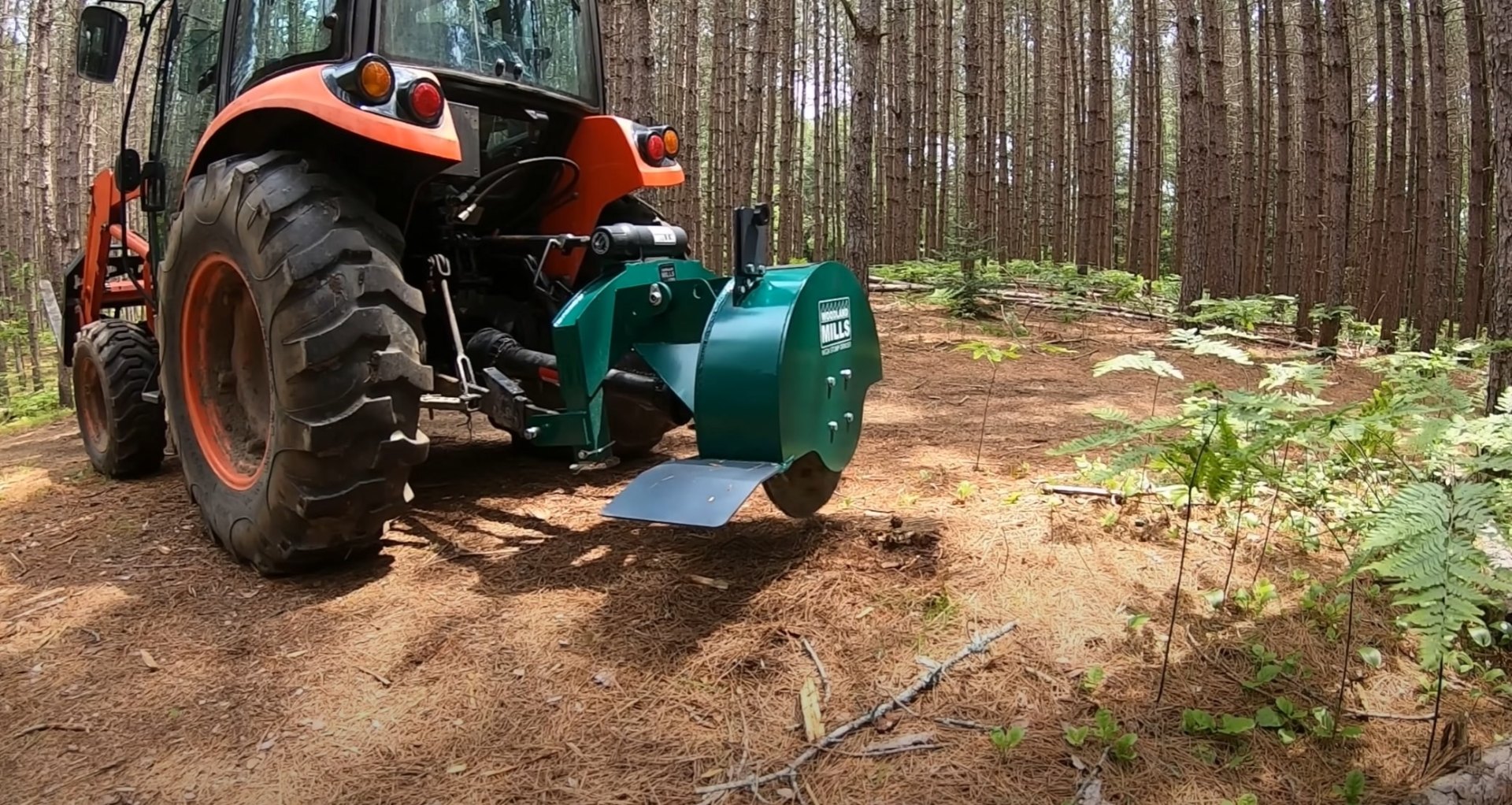 Advanced stump grinding and land clearing equipment for efficient tree service Professional stump grinding equipment attached to tractor working in forest setting